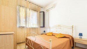 A bedroom with a bed, bedside table, lamp, and window with curtains.