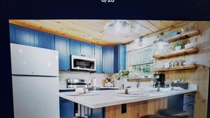 A modern kitchen with a central island, bar stools, and built-in appliances. - Charming 2-bedroom cabin with WiFi, AC in enchanting Blairsville (Blairsville)
