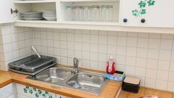 A kitchen with white cabinets, a stainless steel sink, and a wooden countertop. There is a bowl of fruit on the counter and a magazine titled "Carpe Diem".