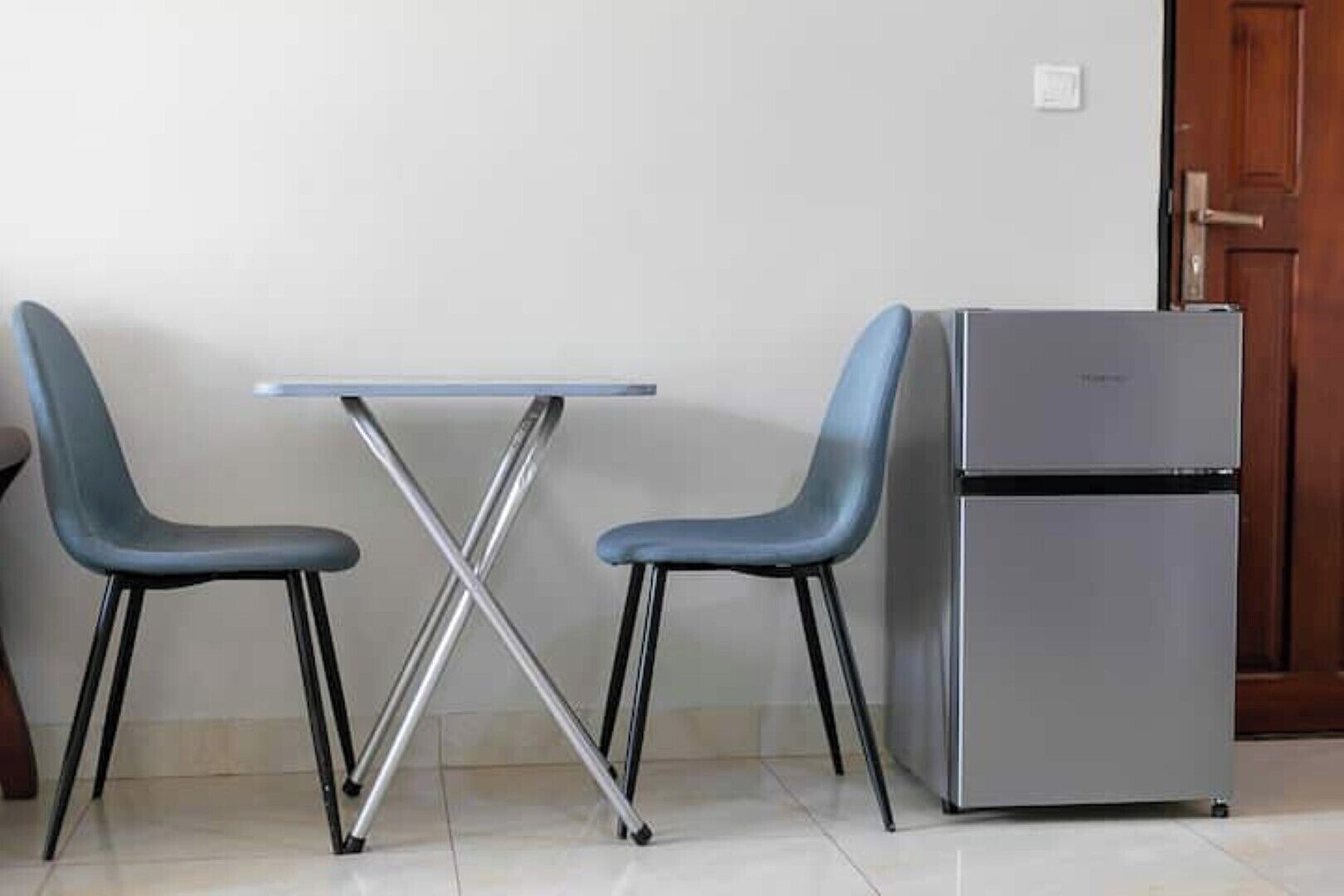 A small kitchenette with a refrigerator and a table with two chairs.