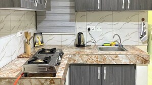 A kitchen with dark wood cabinets, a marble countertop, a gas stove, and a sink with a faucet. - Maryz Secret Haven, cozy one bedroom Air BnB Condo (Kampala)