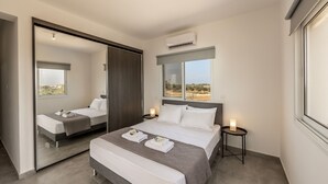 Een moderne hotelkamer met een groot bed, een spiegel, een nachtkastje met een lamp en uitzicht op het woestijnlandschap.