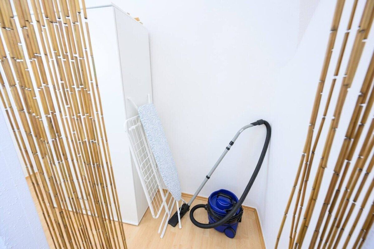 Una habitación con una pantalla de bambú, un tendedero y un aspirador.