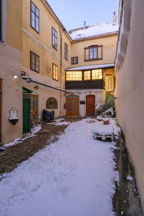 A narrow courtyard with snow-covered ground, a wooden bench, and a building with multiple doors and windows. - City Center Mödling top 1 (Mödling)