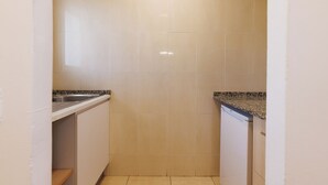 Une petite cuisine étroite, avec des meubles blancs, un plan de travail en granit et un lave-vaisselle.
