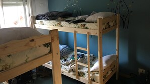 A bunk bed room with a window, a wall mural, and a bed with a floral bedspread. - Phoenix Hostel (San Carlos de Bariloche)