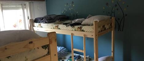 A bunk bed room with a window, a wall mural, and a bed with a floral bedspread.
