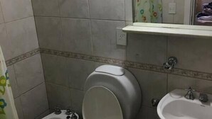 A small bathroom with two toilets, a sink, and a mirror. - Phoenix Hostel (San Carlos de Bariloche)