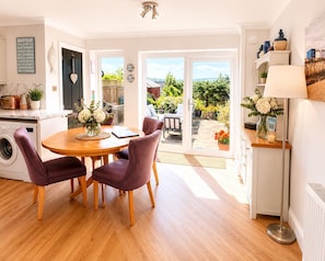 A modern kitchen with a dining area, a washing machine, and a view of the garden. - Sunny Downs (Ryde)