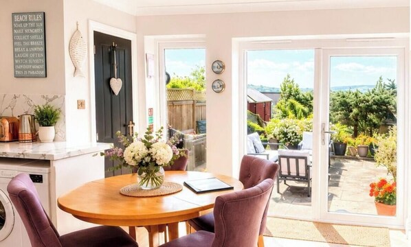 A dining area with a table, chairs, and a vase of flowers. - Sunny Downs (Ryde)