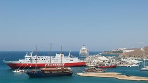 A ferry dock with a large ferry labeled "FAT FERRIS" and a cruise ship in the background. - MEGAS ROOMS (Tourlos)