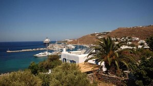 A coastal town with a marina, white buildings, and a hill in the background. - MEGAS ROOMS (Tourlos)