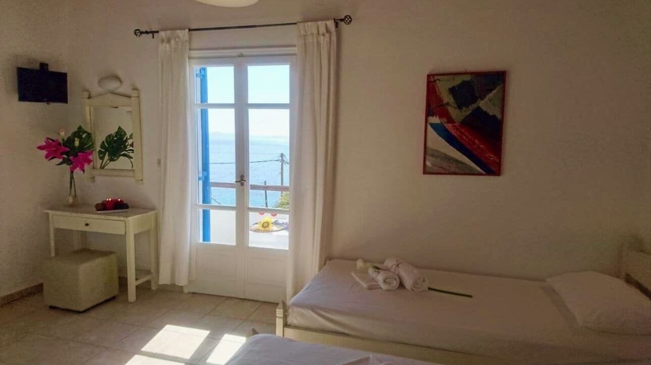 Quarto com cama, escrivaninha, cadeira, janela com cortinas e um quadro na parede.