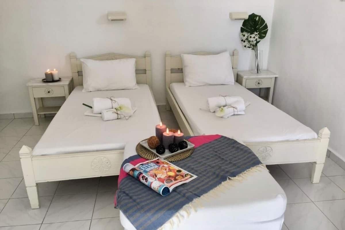 A hotel room with two beds, a small table with candles, and a magazine on the floor.