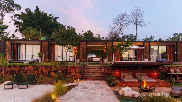 A modern house with a stone wall, a fire pit, and a pathway leading to a seating area. - Solar La Luna (Sao Pedro)