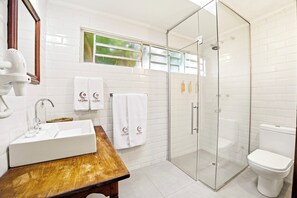 A bathroom with a white sink, wooden vanity, two towels with 'La Luna' branding, a glass shower enclosure, and a toilet. - Solar La Luna (Sao Pedro)