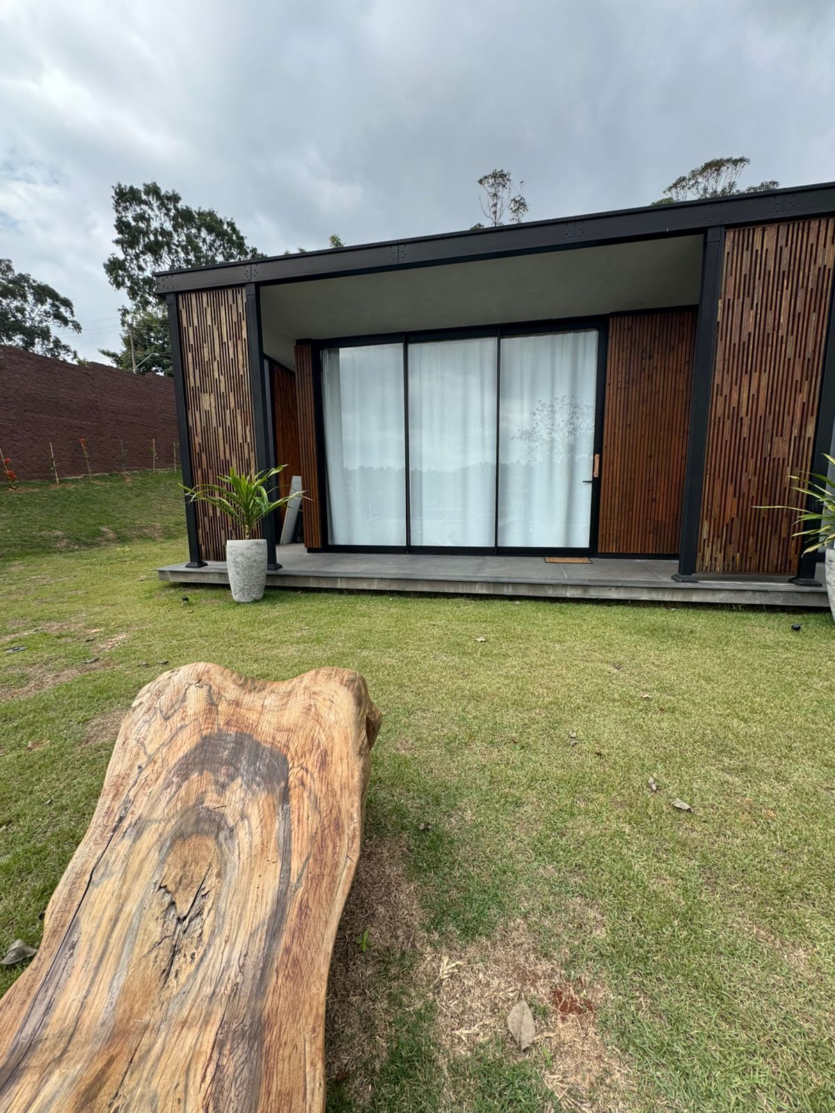 Uma casa moderna com uma grande porta de vidro deslizante, um deck de madeira e um toco de árvore no quintal.