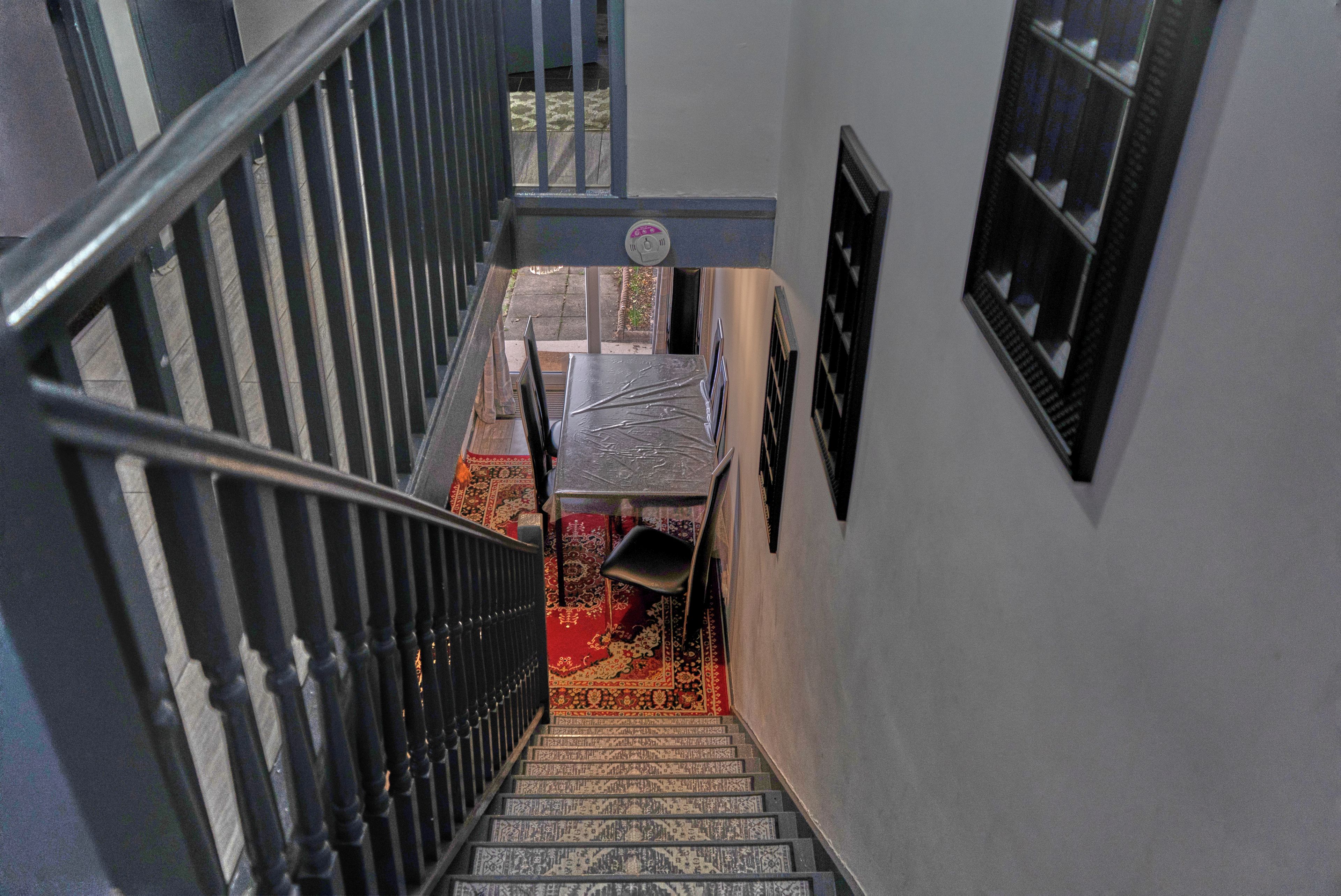 Eine Treppe mit Metallgeländer, einem gemusterten Teppich und einem kleinen Tisch mit Stuhl.
