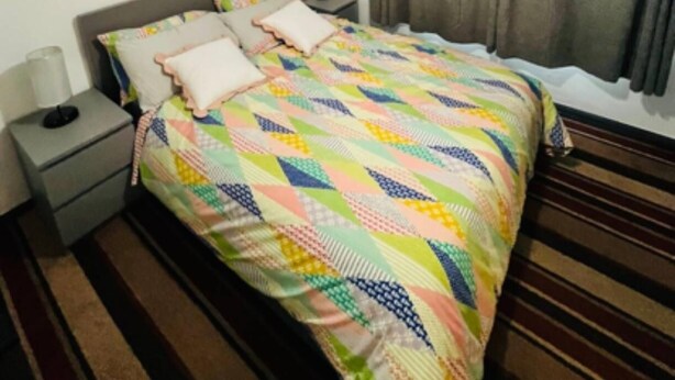 A hotel room with a bed, a nightstand, a chandelier, and a window with curtains. - Surrey Hills Retreat - 2 Bed - Easy Access to Central London (Ash)
