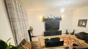 A living room with a sofa, a TV, and a patterned rug. - Surrey Hills Retreat - 2 Bed - Easy Access to Central London (Ash)