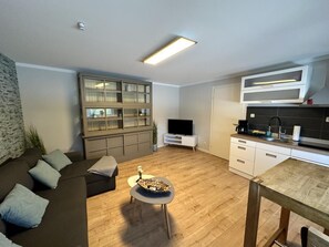 A modern living room with a sofa, a small round table, and a television.