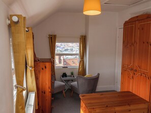 A small, cozy room with a wooden wardrobe, a desk with a chair, and a view of the city through a window. - Harbour View (Whitby)