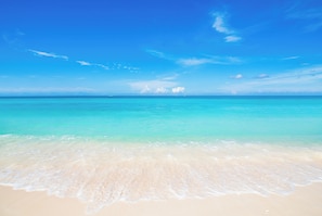 A beach with clear turquoise water and a sandy shore.