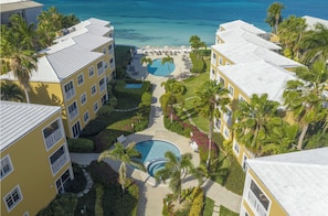 A resort with multiple buildings, a central pool, and a view of the ocean.