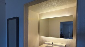 A bathroom with a white sink, a mirror, and a door.