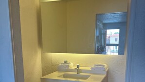A bathroom with a white sink, a mirror, and a window.