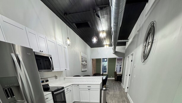 Una cocina moderna con electrodomésticos de acero inoxidable, armarios blancos y un suelo de madera con diseño de espiga.
