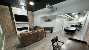 Una sala de estar moderna con un sofá modular, una mesa de comedor con sillas, una chimenea y una zona de cocina.