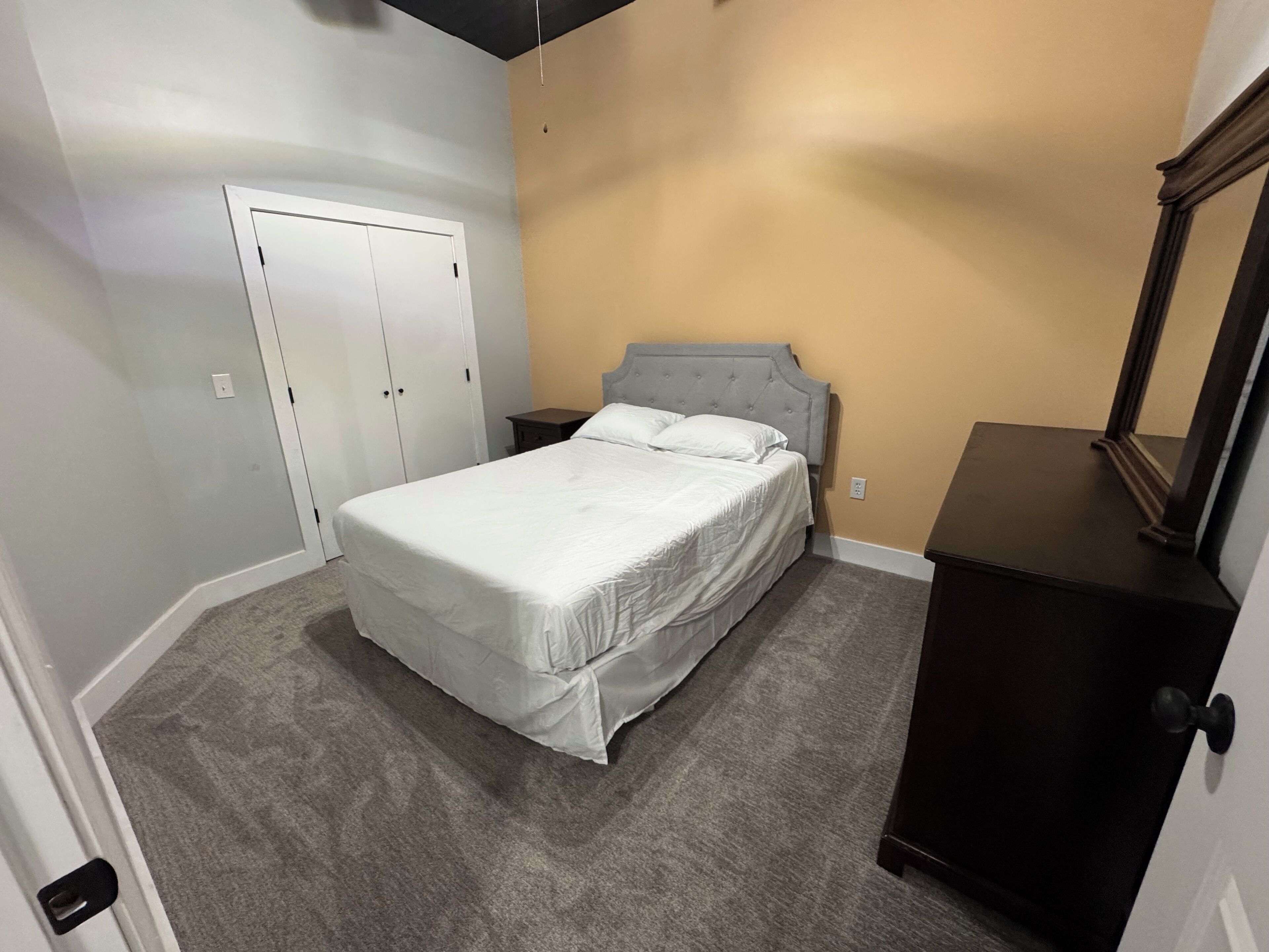 Un dormitorio con cama, mesita de noche, cómoda y armario.