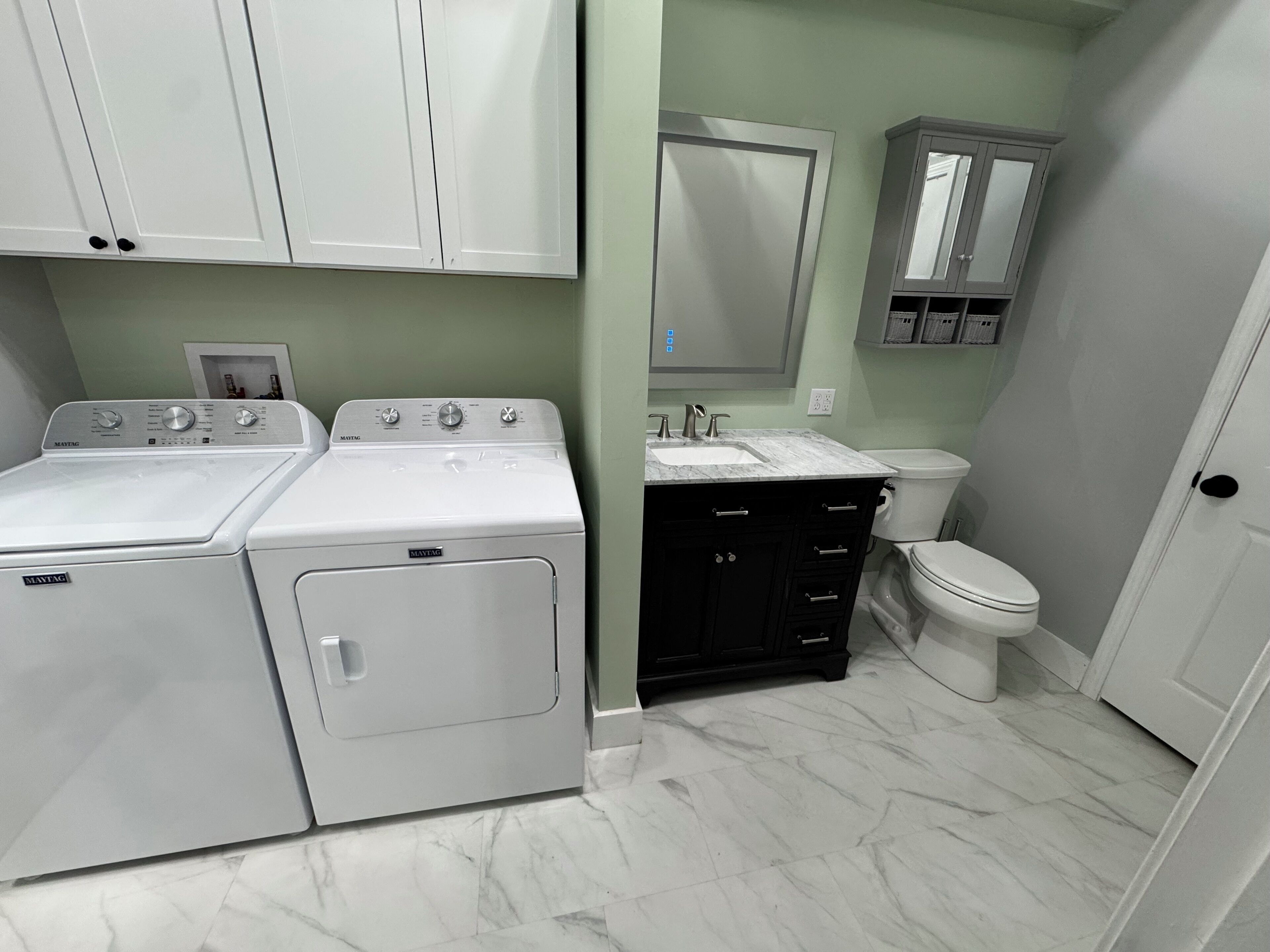 A laundry area with two Maytag washers and dryers, a sink, and a toilet.
