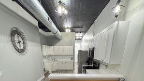 Una cocina moderna con armarios blancos, una isla de madera con taburetes altos y luminarias colgantes.