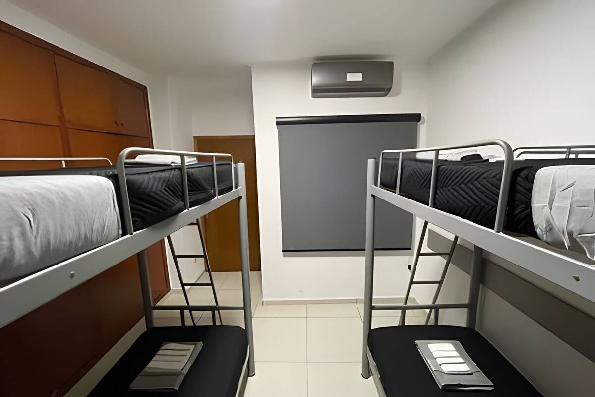 A dormitory room with bunk beds, a wardrobe, a heater, and a whiteboard.