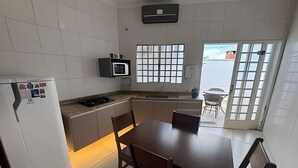 Una cocina compacta con refrigerador, microondas y un pequeño comedor con mesa y sillas.