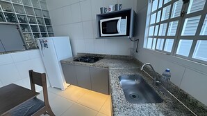 Cocina compacta con microondas integrado, lavamanos y un pequeño comedor.