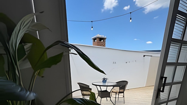 Vista desde un balcón con una planta en maceta, una mesa y sillas.