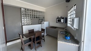 Cocina compacta con mesa, sillas, microondas y pileta.