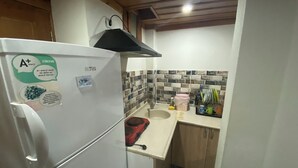 Eine kleine Küche mit einem weißen Kühlschrank, einer Spüle und einer gefliesten Spritzschutzwand.
