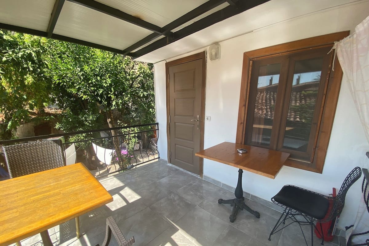 A balcony with a wooden table and chairs, a window with a view, and a door.