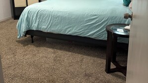 Un dormitorio con una cama, un tocador, una mesita de noche y una ventana con cortinas.