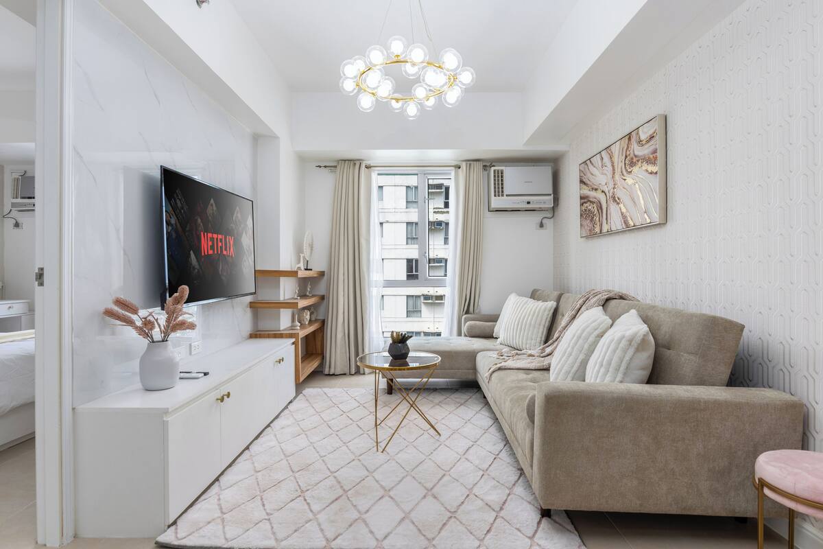 Una sala de estar moderna con televisión, sofá y elementos decorativos.