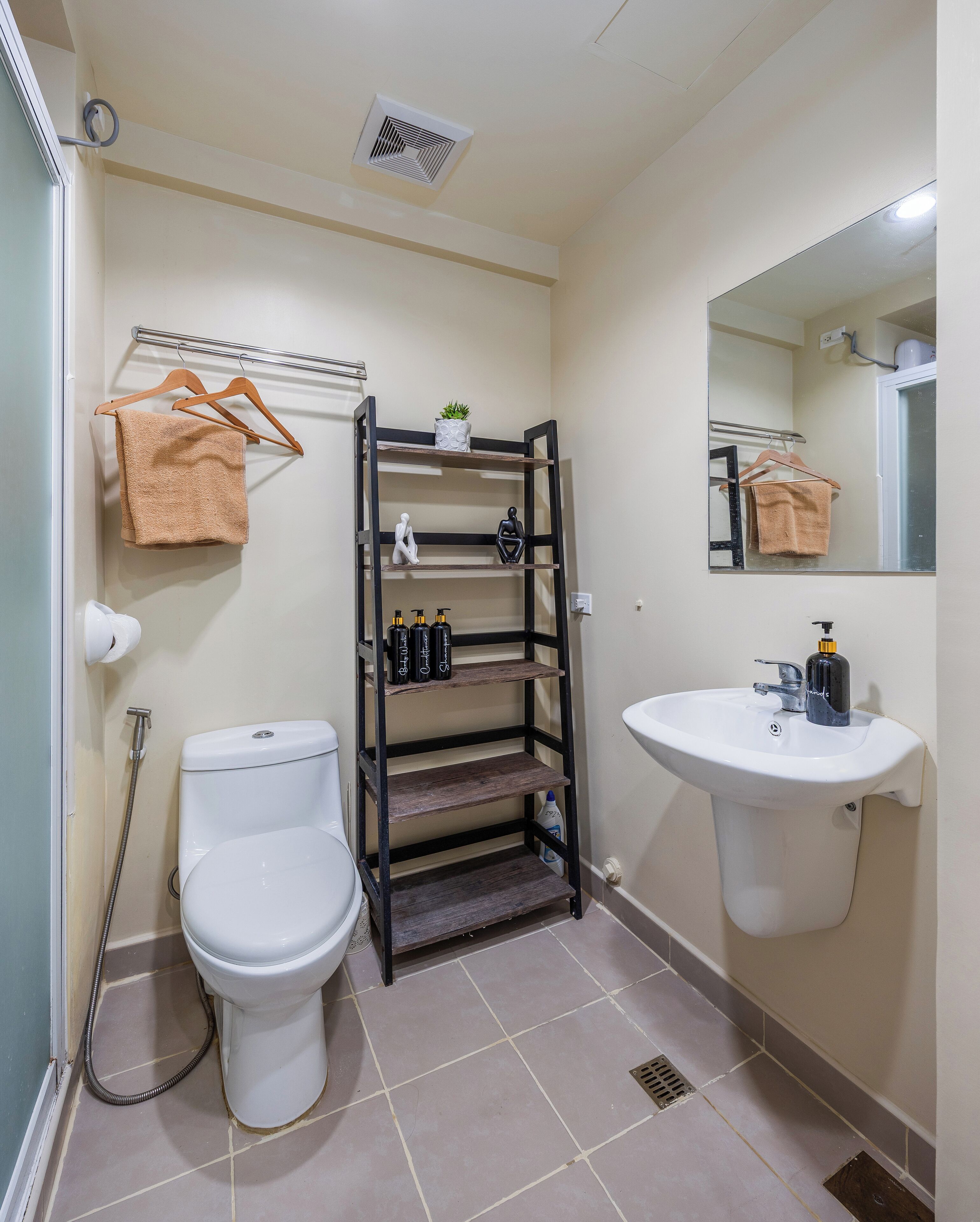 Ein Badezimmer mit Toilette, Waschbecken, Ablagefach für Toilettenartikel und Handtuchhalter.
