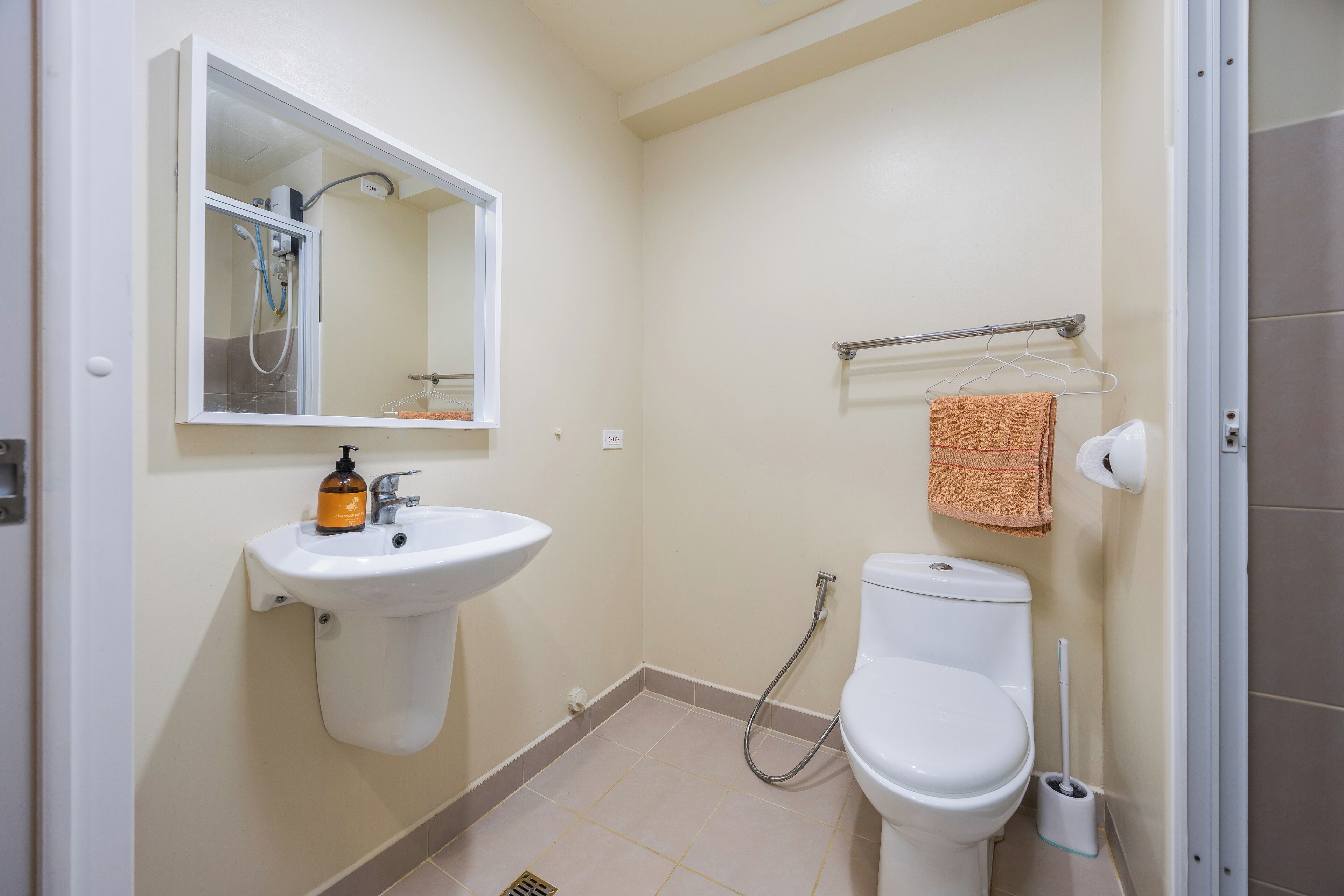 A bathroom with a sink, mirror, toilet, and towel rack.