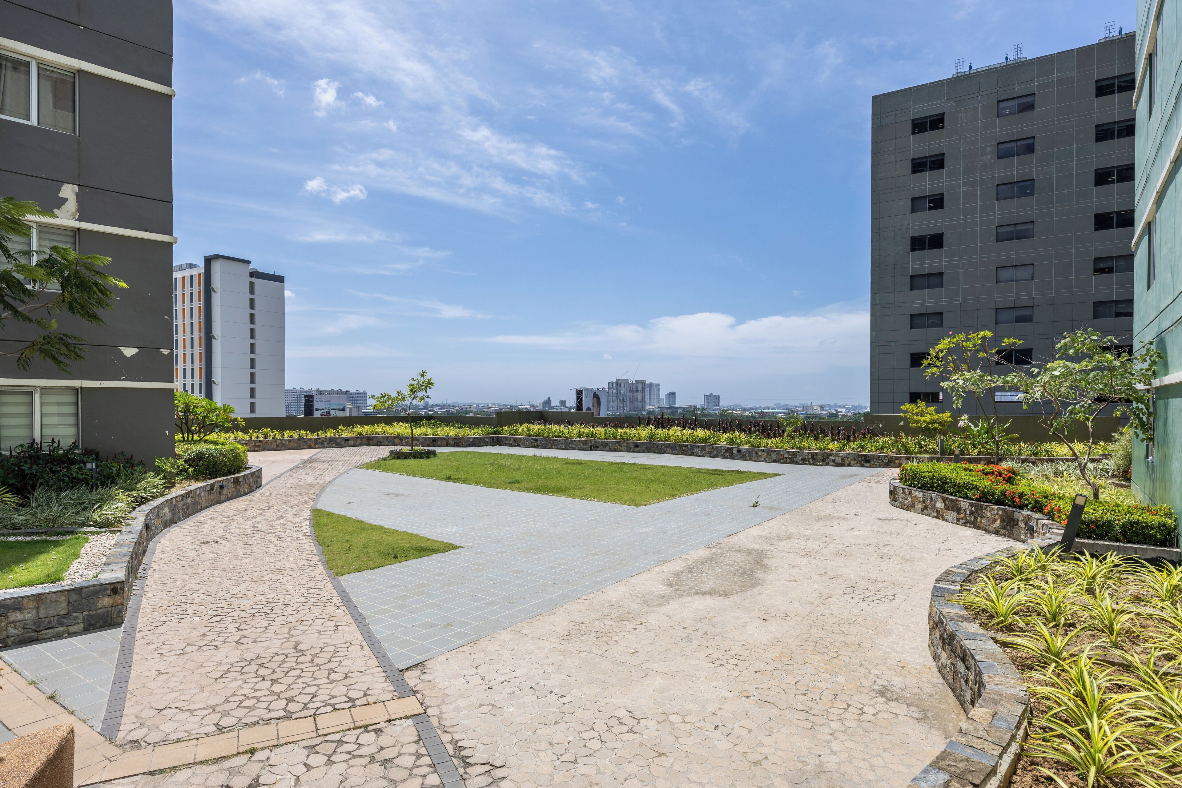 A landscaped courtyard with a curved pathway, surrounded by buildings and greenery.