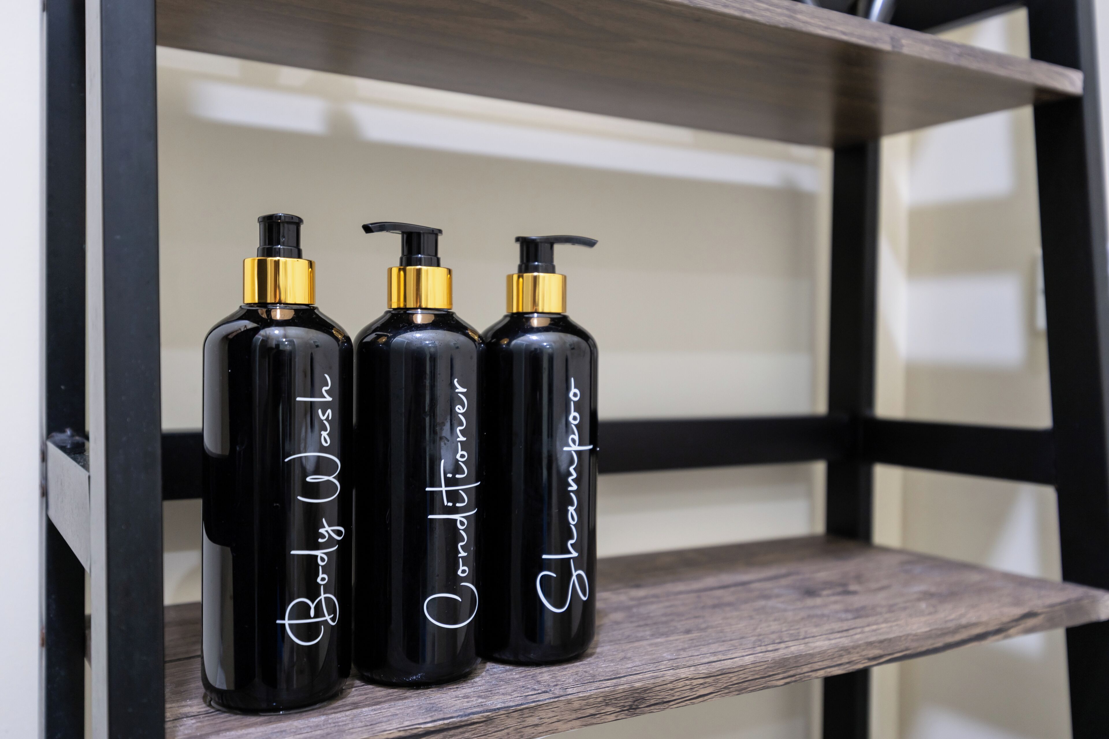 Three black bottles with gold caps on a wooden shelf.