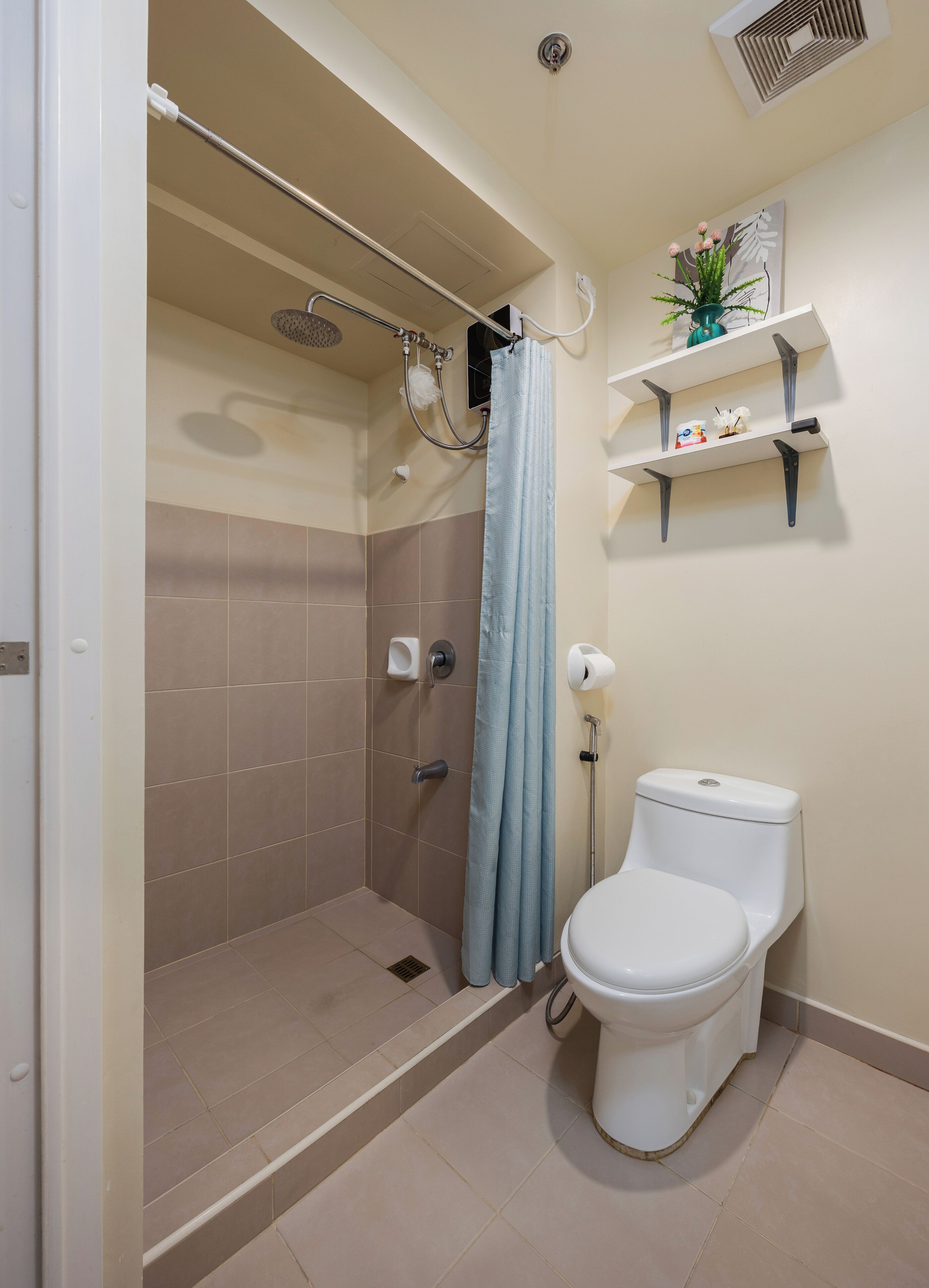 Une salle de bain avec douche, toilettes et une étagère contenant des articles de toilette.