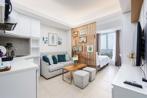 A modern living room with a sofa, ottomans, a coffee table, and a TV. - Avida Riala IT Park - Virgo Nest Rentals (Cebu)